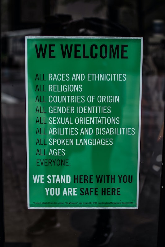 Áp phích có nội dung Chúng tôi hoan nghênh tất cả các chủng tộc và sắc tộc, mọi tôn giáo, mọi quốc gia xuất xứ, mọi bản dạng giới, mọi khuynh hướng tình dục, mọi khả năng và khuyết tật, mọi ngôn ngữ nói, mọi lứa tuổi. Mọi người. Chúng tôi đứng đây cùng bạn. Bạn được an toàn ở đây.